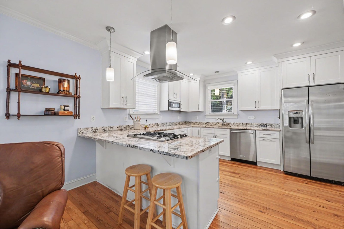 Renovated kitchen with white cabinetry, granite counters and a gas range