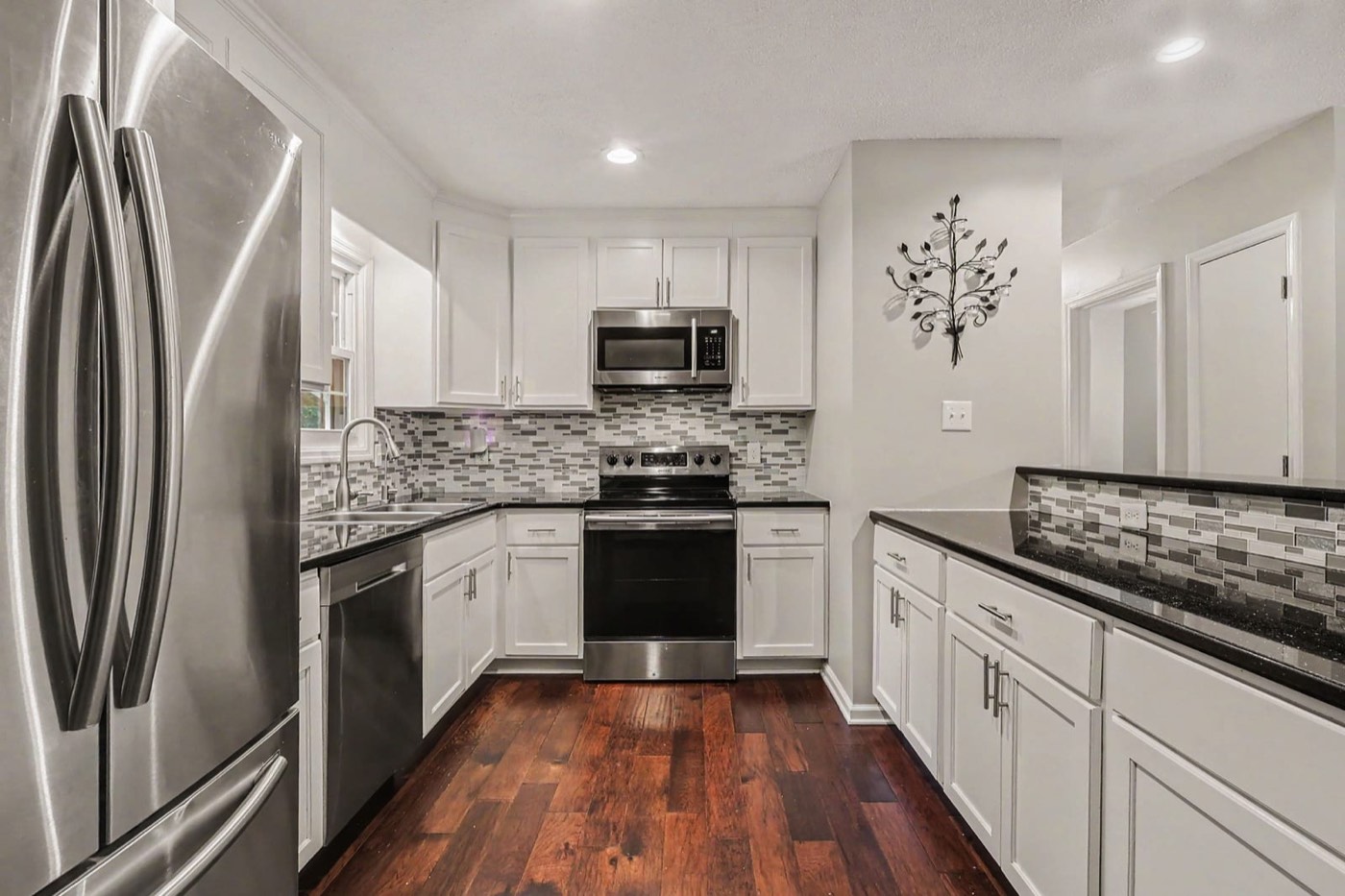 White kitchen with stainless appliances and a tile backsplash