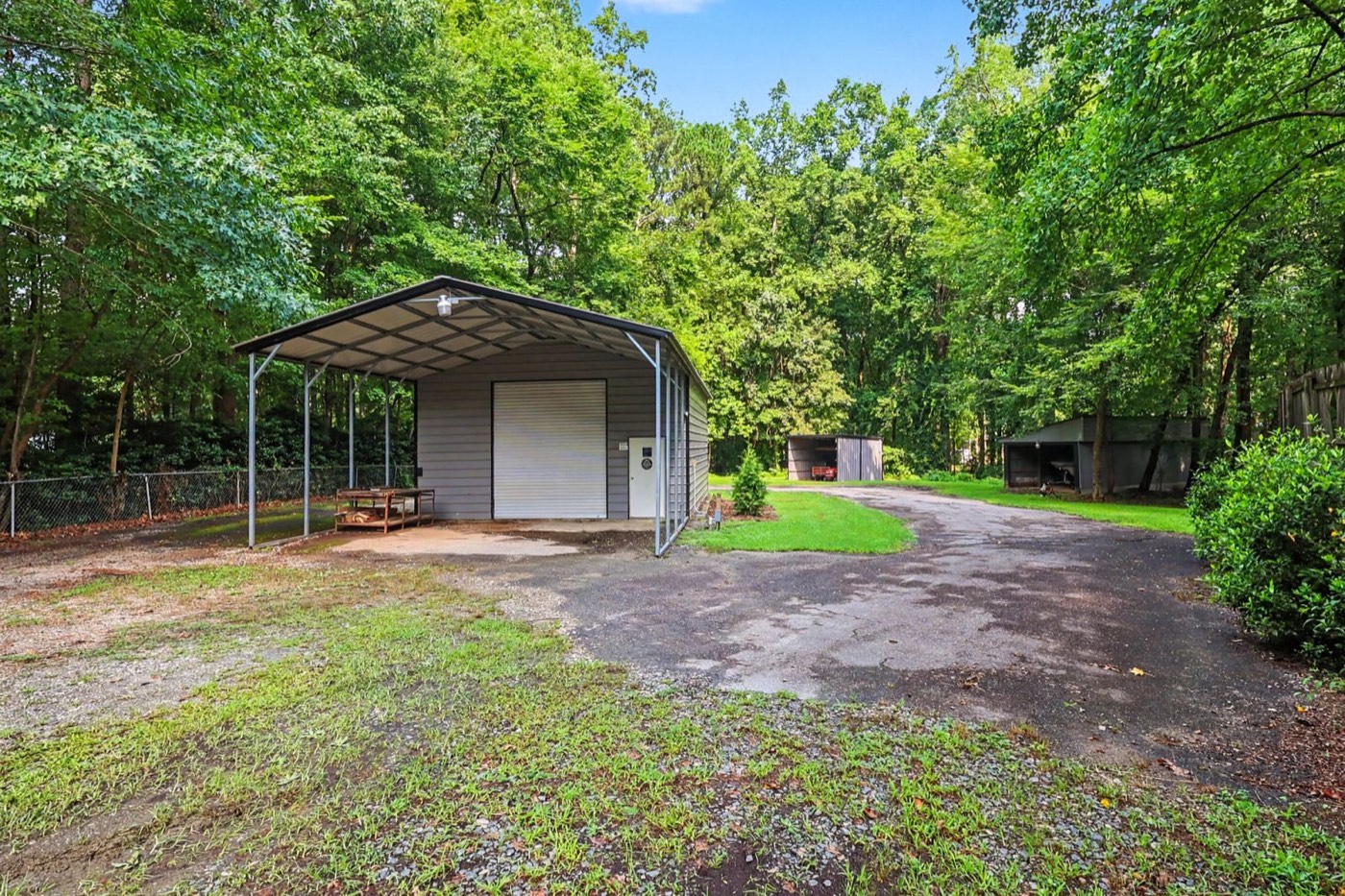 Gated gravel drive leading to the detached shop and carport